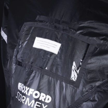 Sort Oxford Stormex MC-cover med gennemsigtig lomme til solcelleoplader og hvidt logo.